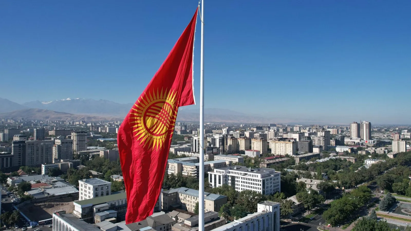 Флаг Кыргызстана на фоне неба и города